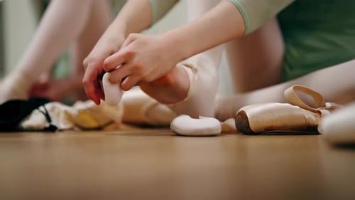 École de ballet professionnelle en gros plan pour enfants Les ballerines enfilent des chaussures à pointes lorsqu'elles sont assises