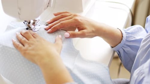 Woman's Hands Guide Fabric Through a Sewing Machine