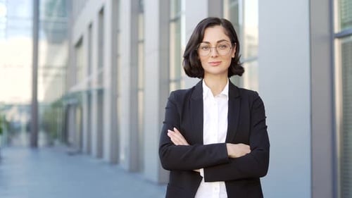 Portrait of a young serious businesswoman standing on the street near an office building. Confident