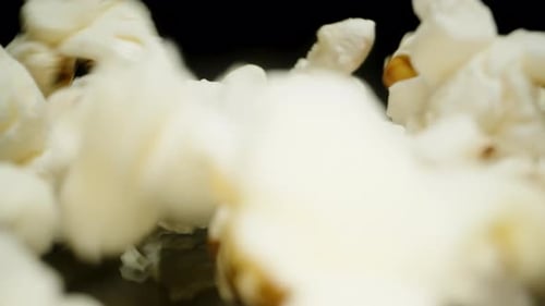 La caméra s'éloigne du pop-corn qui tombe sur la table, mais le couvre complètement. Macro lente