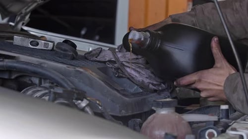 Mechanic Filling Oil in Car Engine