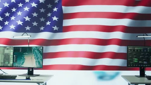 Workplace with American Flag Behind Computer Monitors