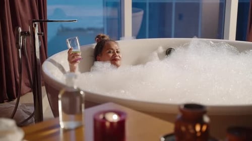 Woman Relaxing in Luxurious Bubble Bath with Drink