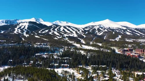 Aerial Drone View of Snow Covered Winter Mountain Peaks with Ski Trails Ready for Outdoor Sports and