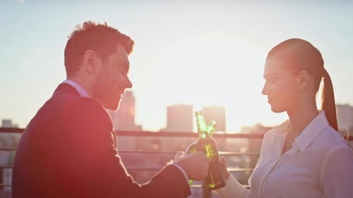 Man and Woman Toasting Beers on Rooftop