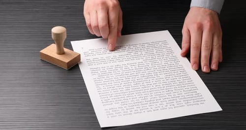 Man Reviews Typed Document with Stamp Tool in Office