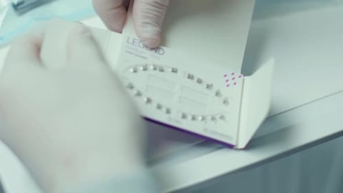 Manos de cerca: el dentista sostiene material dental, soportes e instrumentos, recepción en el ortodoncista