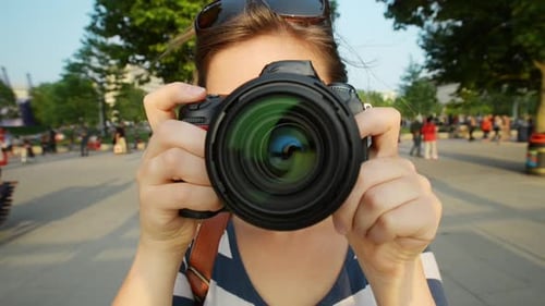 4k video footage of a young woman taking pictures with a camera while exploring a city