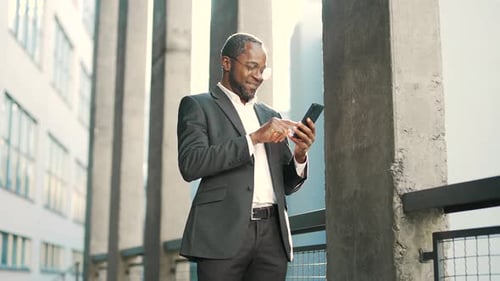 Man in Blazer Uses Smartphone Outdoors