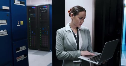 4k video footage of a young woman using a laptop while working in a server room