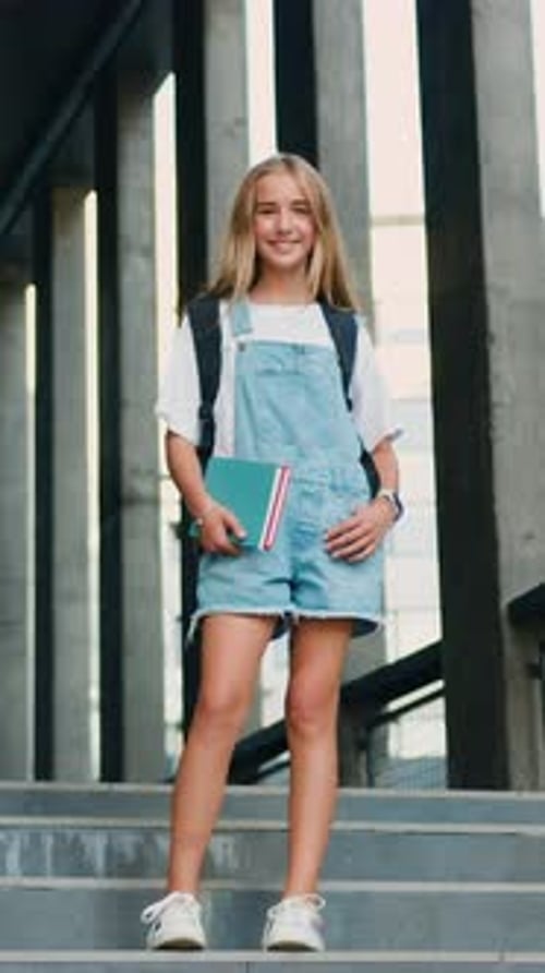 Cheerful Girl Hugging Books Posing with Backpack Near School Building Outdoor Smiling to Camera