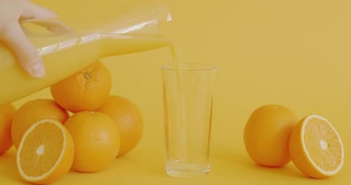 Orange Juice Being Poured Into Glass on Yellow