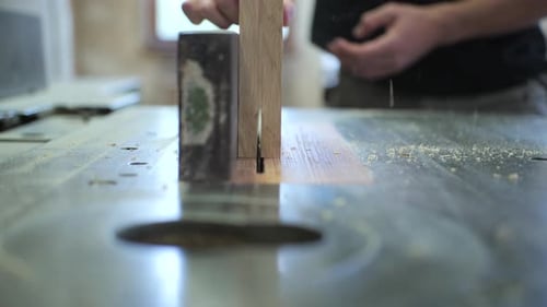 carpenter cutting wooden frame in half with circular saw, frontal view, slow motion