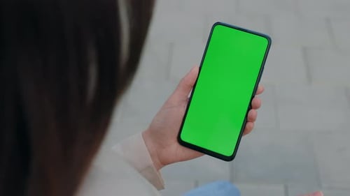 Chroma Key MockUp on Smartphone in Hand Woman Holds Mobile Phone and Tapping on Photos or Pictures