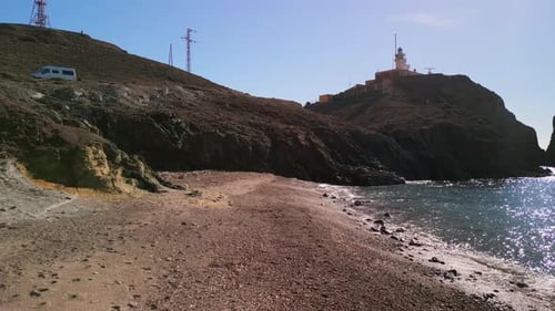 Luftaufnahme eines Strandes in Almeria mit einem Leuchtturm im Hintergrund