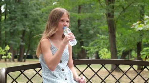 Preteen 11 Years Old Girl Drinking Clean Water From a Bottle Outdoors in Park
