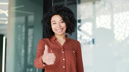 Smiling Woman Giving Thumbs Up in Office