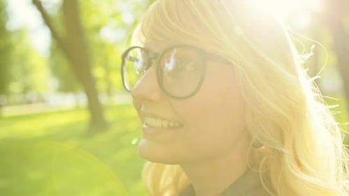 Visage d'une blonde heureuse avec des lunettes dans un parc d'été