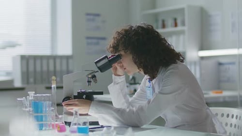 Lab Assistant Using Microscope in a Brightly Lit Lab