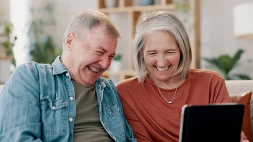 Senior Couple Laughing Together at Tablet at Home