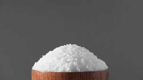 White Table Salt Granules Falling Into a Pile Wood Bowl Gray Color Studio Background Condiment
