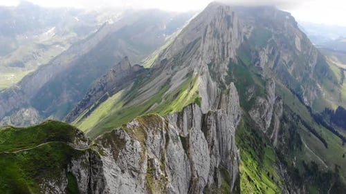 Aerial flyover over the cliffs of Schafler ridge in Appenzell, Switzerland with pan up towards the m