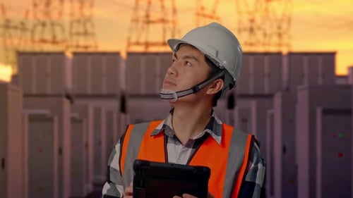 Close Up Of Asian Male Engineer Looking At The Tablet In His Hand with High Voltage Power