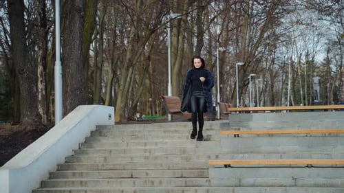 Beautiful girl in the park. Happy young woman goes down the stairs in the park.