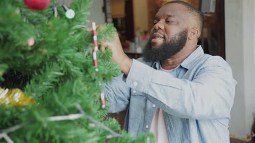 Man Decorating Christmas Tree at Home