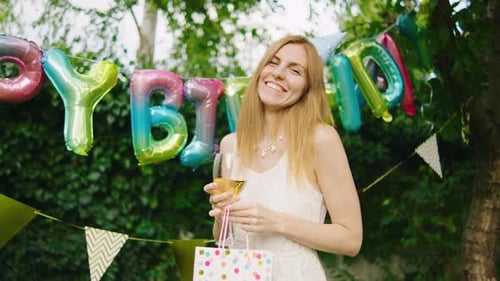Woman Celebrating Birthday Outdoors With Balloons and Wine