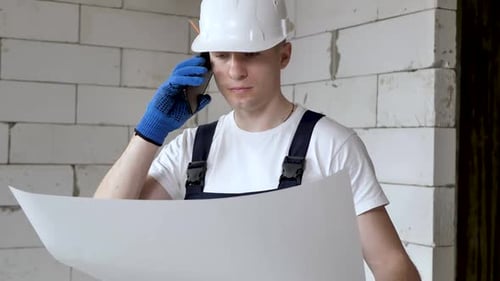 Portrait of the Architect Builder Studying the Layout Plan of the Premises and Talking on the Phone