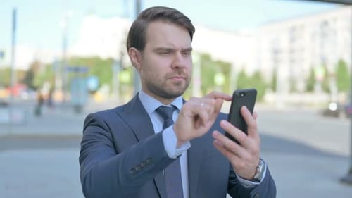 Man in Suit Using Smartphone in City