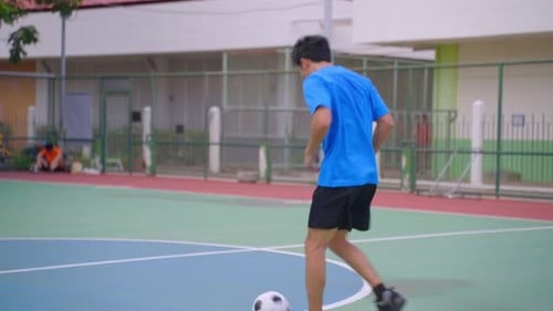 Asian young sportsman practicing football playing in the outdoors stadium