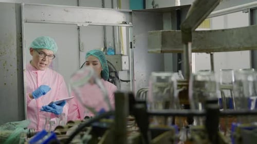 Dans l'usine de boissons, deux ingénieurs de machines discutent du contrôle qualité à l'aide d'une tablette numérique