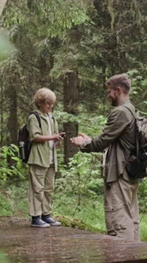 Boy Sprays Insect Repellent on Hands in Forest