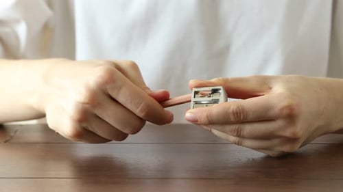 Woman sharpening a pencil with a sharpener tool