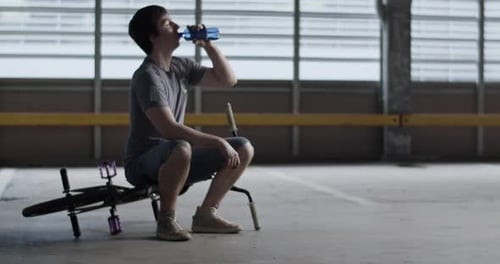 Young Man Drinks Water Bottle Next To Bike