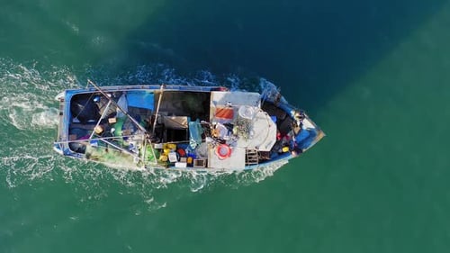 Large Fishing Boat loaded with Fishing nets heading out to sea, Aerial view.