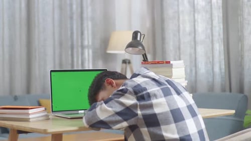 Bored Teenager Yawning And Sleep With Green Mock Up Screen Laptop At Home While Doing Home Work