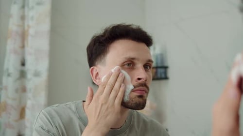 Man Applying Cleansing Foam to Face in Bathroom