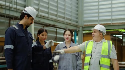 Diverse team of factory workers and engineer putting hands together and cheering for success