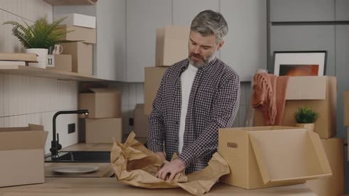 Man Packs Dishes in Kitchen for Moving