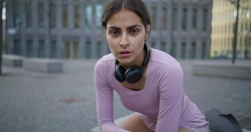 Müde Joggerin macht Pause nach hartem Training im Freien, ruht sich aus und atmet tief durch, trägt Sport...