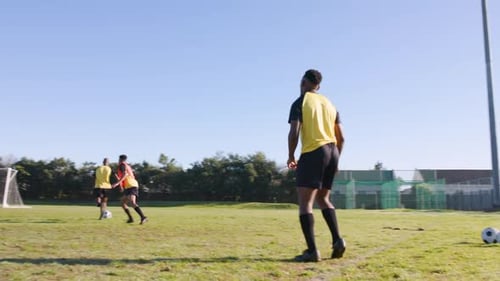 Playing soccer on field, men in sportswear training and passing ball