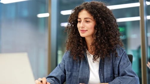 Confident Businesswoman Smiles at Camera in Modern Office Setting