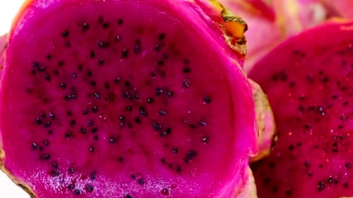 An extreme closeup of a bright pink dragon fruit sliced showing the shape of the seeds