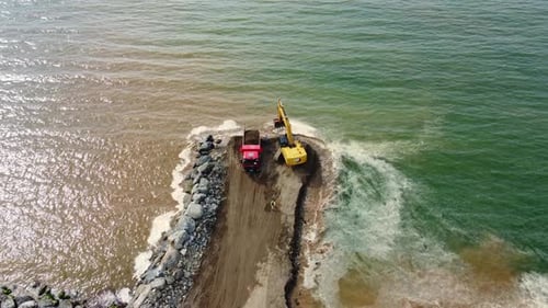 Excavator loading dump truck on lake shore