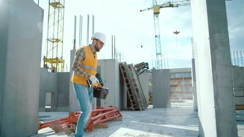 Construction Worker With Tools Walking on Building Site