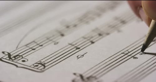 Un músico compositor escribe, en el pentagrama vacío, las notas de su nueva canción u ópera. La música