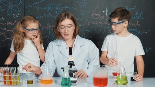 Caucasian boy mixing chemical liquid while teacher giving advice. Erudition.